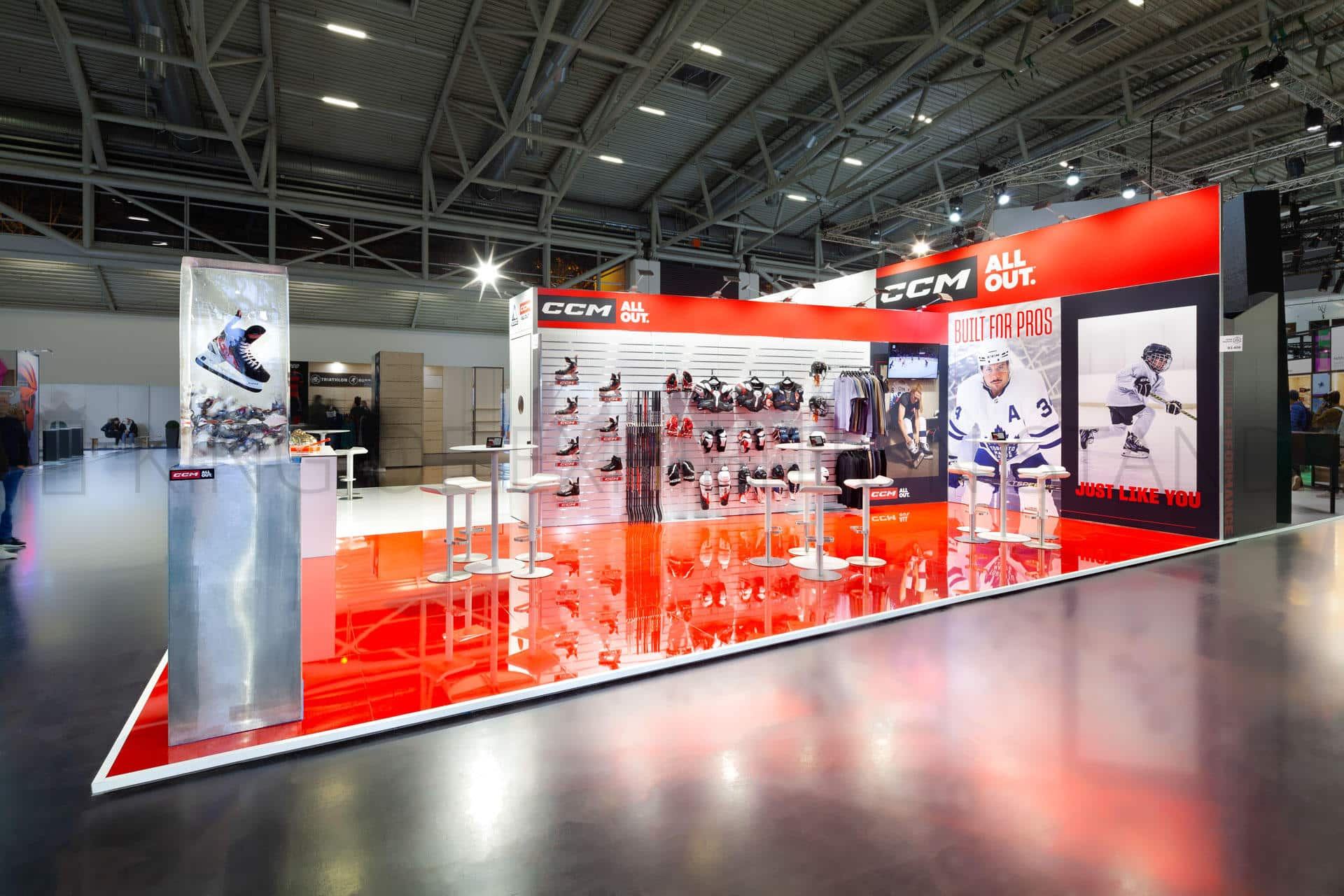 Long red and white stand with a lit product wall of ice hockey skates and sticks