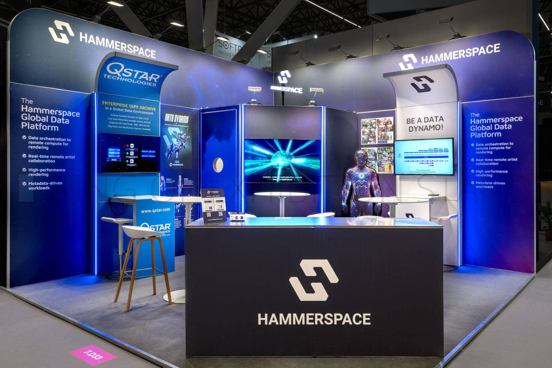 Dark blue stand with backlit walls, a central screen and a black reception desk