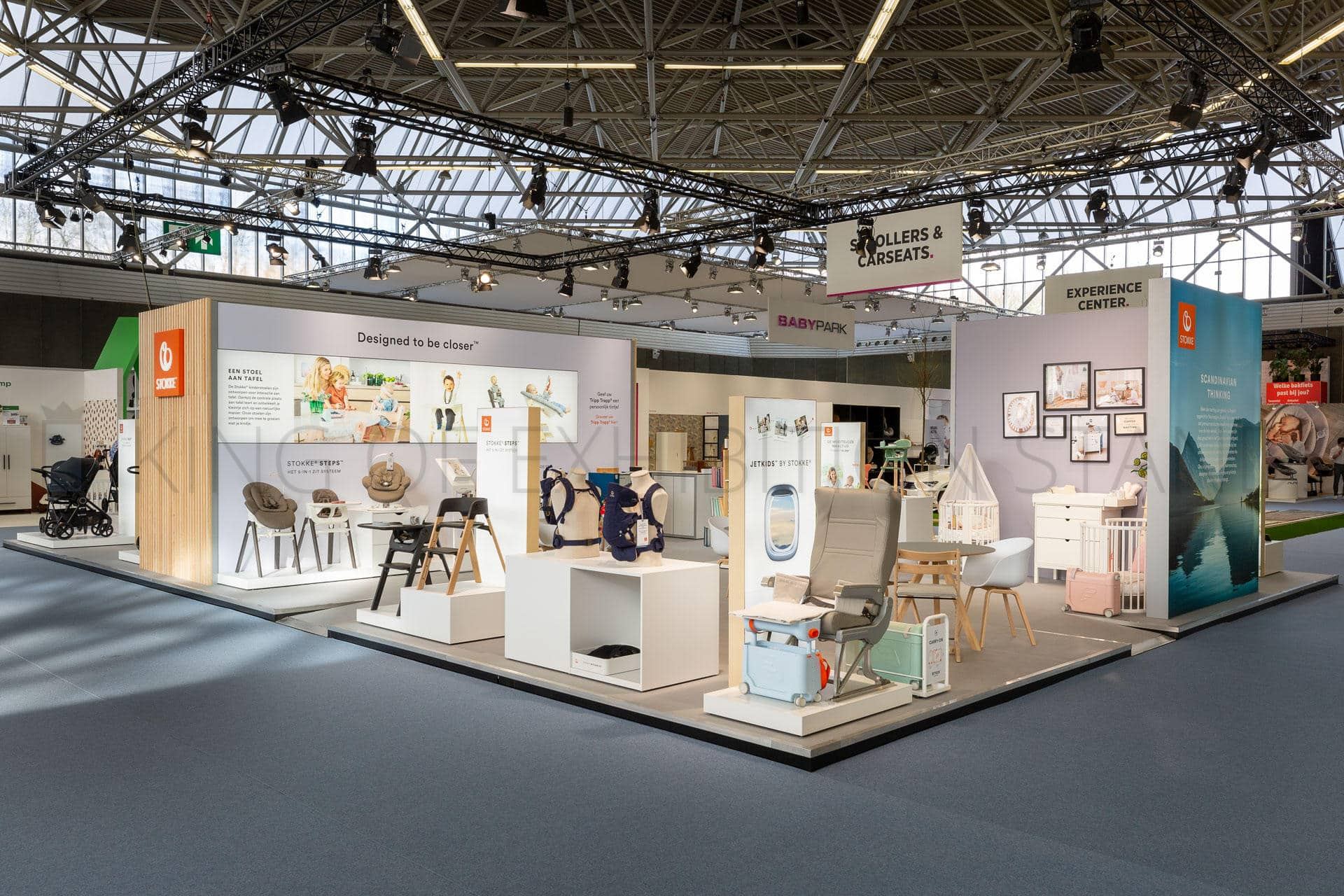 Open island stand with oak slats, a nursery room set and pushchairs on a pale floor